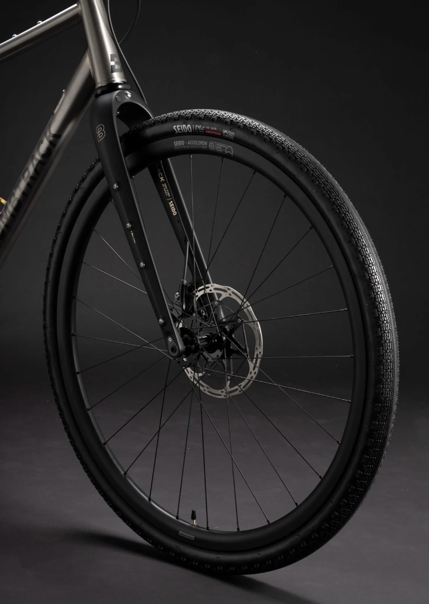 Close-up of a Bombtrack front wheel and carbon fork highlighting the disc brake and Seido rim.