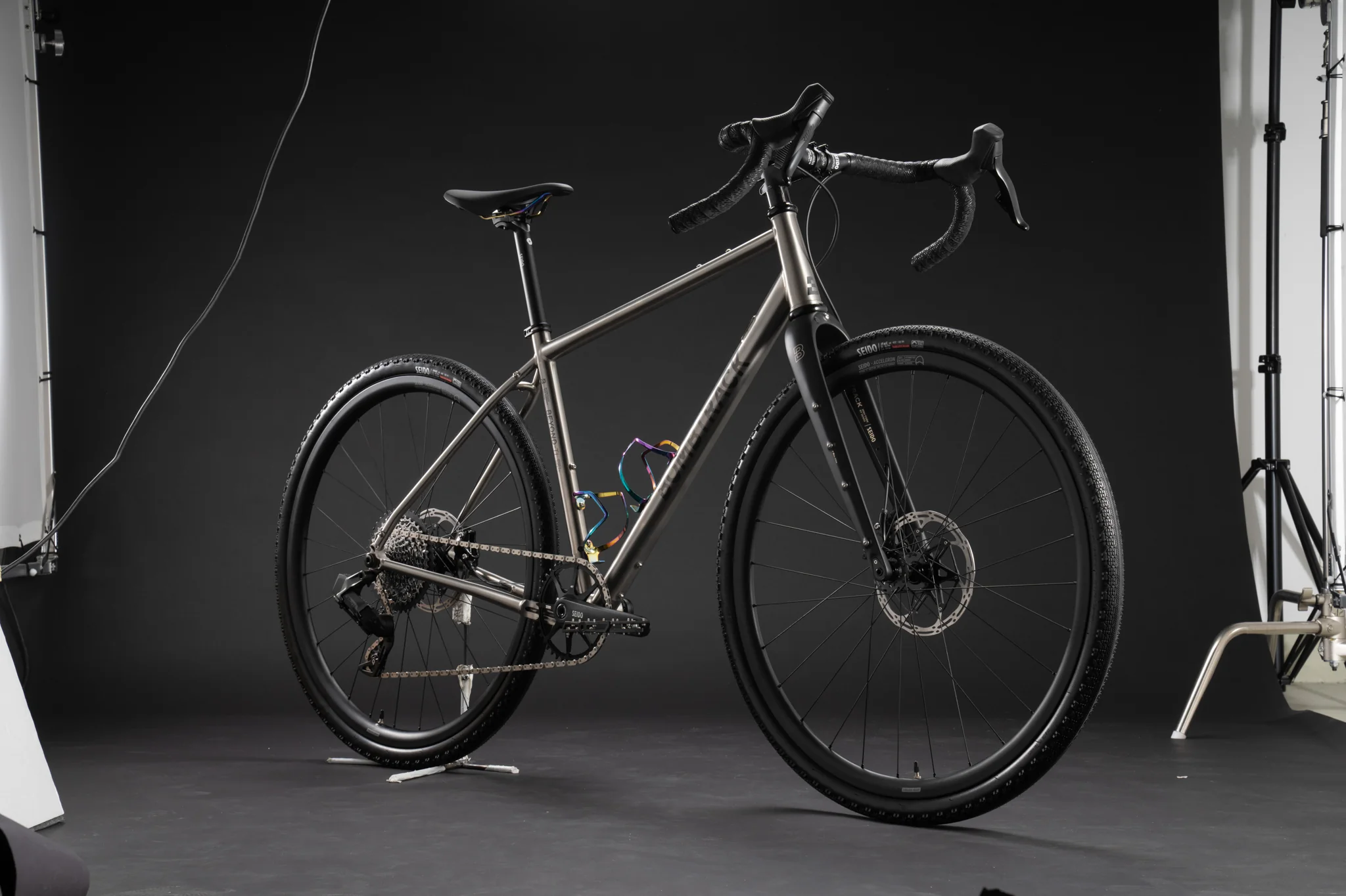 Full studio shot of a Bombtrack titanium gravel bike with lighting equipment visible.