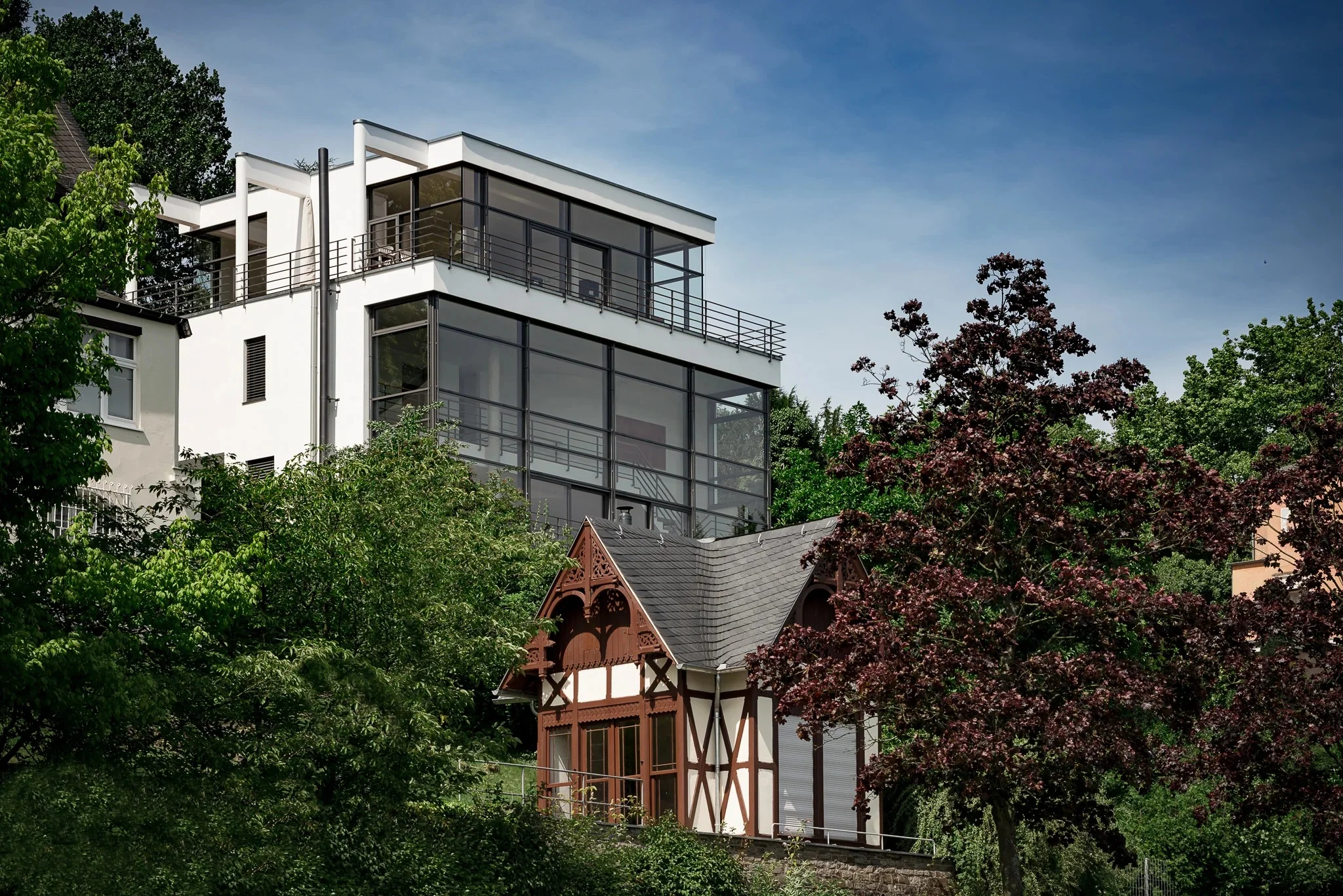 Exterior view showing the modern glass facade of the villa next to traditional architecture.